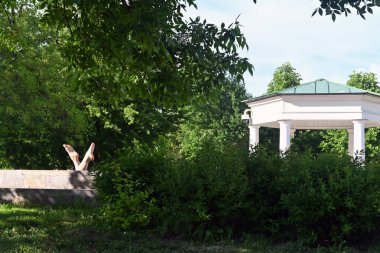 Bir yaz günü insanlar bahçede dinlenir. Ağaçların manzarası, çardakların manzarası, St. Petersburg 'un eski merkezindeki Yusupov Bahçesi' ndeki bir kadının bacakları. St. Petersburg sakinleri için dinlenme yerleri. Vatandaşların yaz tatili.