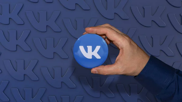 Uma Mão Segurando Logotipo Vkontakte Distintivo Brilhante Sobre Fundo Azul — Fotografia de Stock