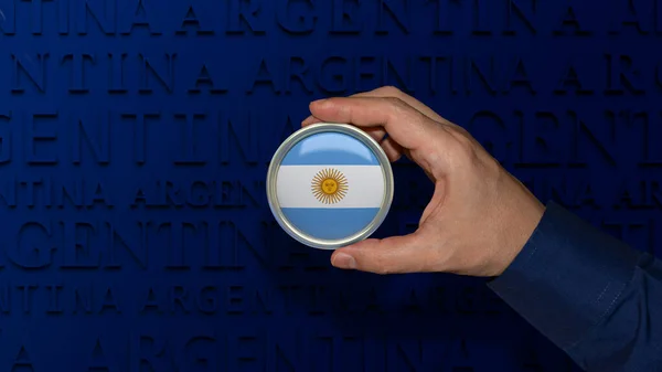 A hand holding an Argentinian\'s national flag badge over dark blue background