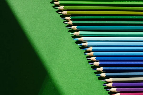 Colour pencils. Yellow. Green. Blue. Blue. Many flowers. Close-up. Green background. Place for your text. Close-up.