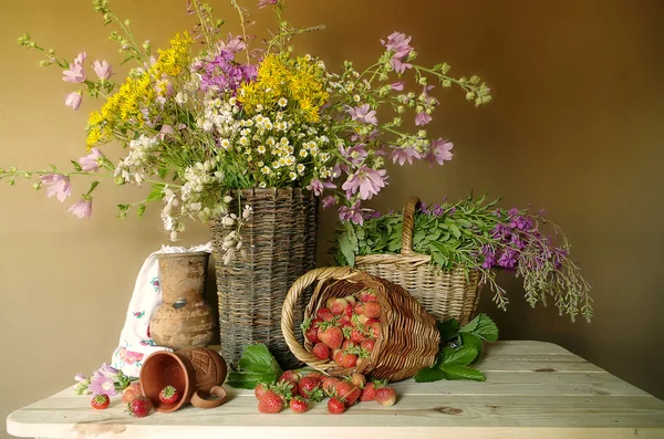 Çilek ve çiçeklerle natürmort. Kırmızı, olgun çilek ve kır çiçekleri ve ayçiçeği bir buket .
