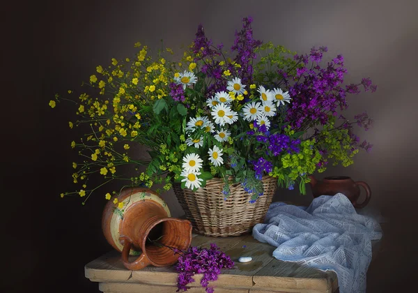 Flores silvestres en un jarrón y bayas en la cesta — Foto de Stock