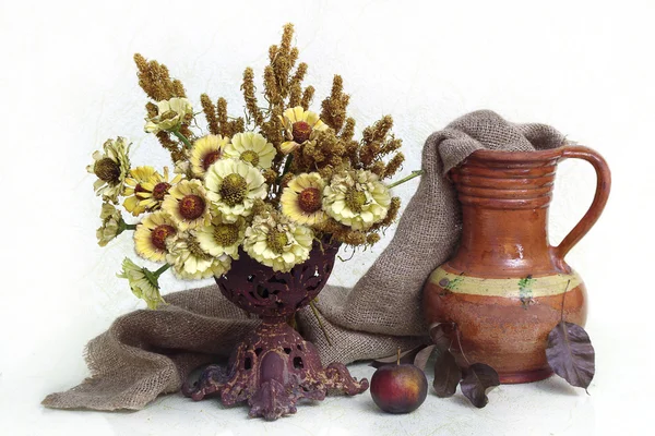 Yellow flowers in a vase and a jug from clay on a white background. — Stock Photo, Image