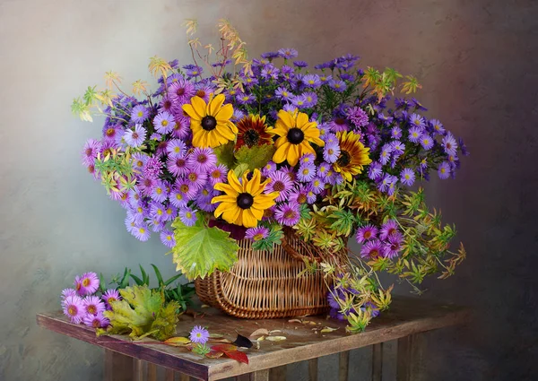 Masanın üzerindeki sepetin içinde güzel bir buket sonbahar çiçeği..