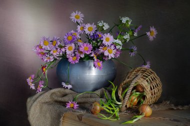 Vazoda renkli papatyalar ve masada soğanlar..