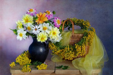 Bir vazoda yıldız çiçeği ve mavimsi bir arka planda çiçek çelengi..