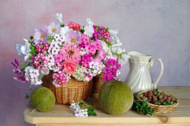 Masadaki sepetin içinde pembe bir buket çiçek..