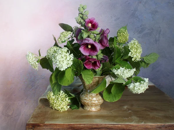 Still life with white flowers and hydrangeas on a multicolored background.Garden flowers in a bouquet.