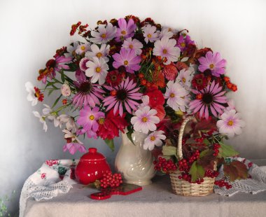 A beautiful bouquet of flowers in a white vase with red berries . clipart
