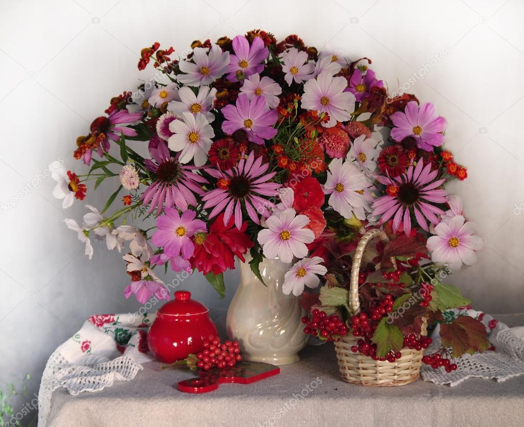 A beautiful bouquet of flowers in a white vase with red berries .