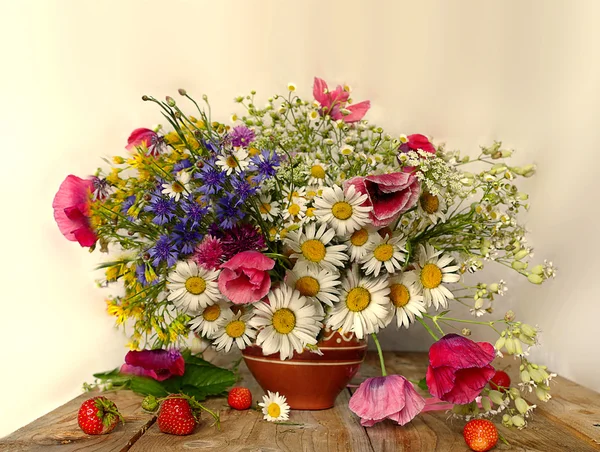 Kil ve kırmızı çilek dan bir vazoda kır çiçekleri