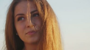 Sahilde kız. gün batımında saçında rüzgar ile