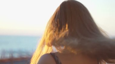 Sahilde kız. gün batımında saçında rüzgar ile