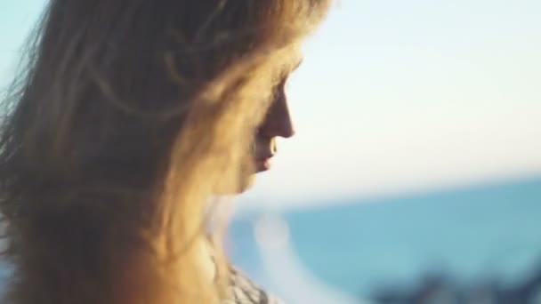 在海滩上的女孩。在日落时与她的头发在风中 — 图库视频影像