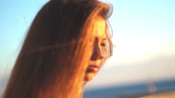 Chica joven en la playa con su teléfono inteligente. Puesta de sol — Vídeos de Stock
