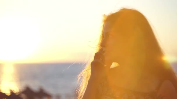 Ung flicka på stranden med din smartphone. Solnedgång — Stockvideo