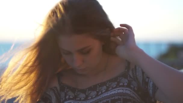 Молода дівчина на пляжі зі смартфоном. Захід сонця — стокове відео