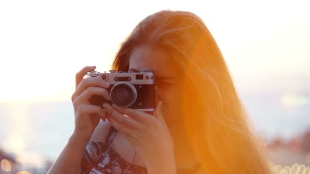 Ragazza con una macchina fotografica vintage. Spiaggia, tramonto, vento — Video Stock