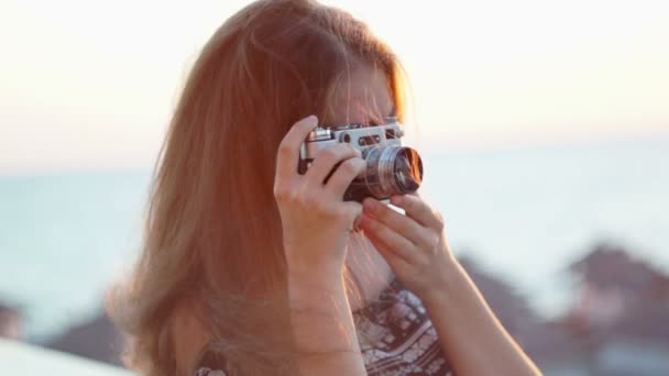 Дівчина з вінтажним фотоапаратом. Пляж, захід сонця, вітер — стокове відео