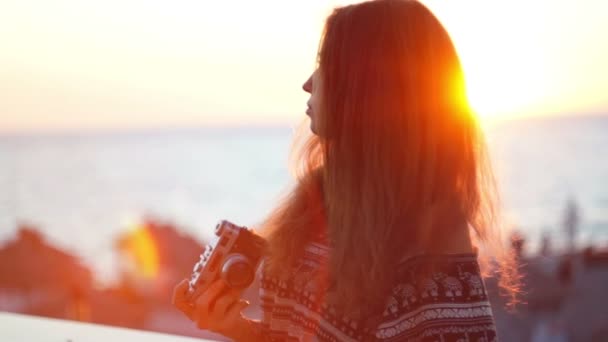 Chica con una cámara vintage. Playa, atardecer, viento — Vídeos de Stock