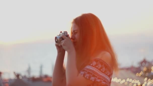 Дівчина з вінтажним фотоапаратом. Пляж, захід сонця, вітер — стокове відео