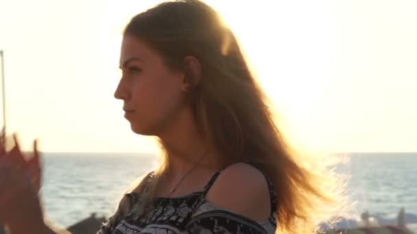 해변에서 여자입니다. 바람에 그녀의 머리와 석양 — 비디오