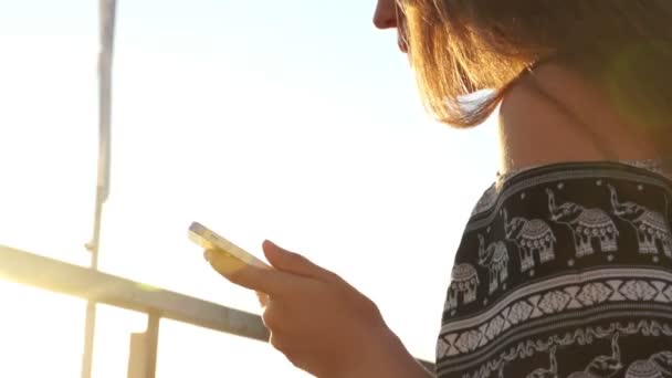 Jong meisje op het strand met uw smartphone. Zonsondergang — Stockvideo