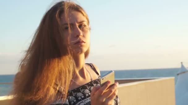 Menina na praia com o seu smartphone. Pôr do sol — Vídeo de Stock