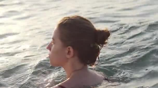 Крупним планом портрет молодої дівчини плаває в морі на заході сонця — стокове відео