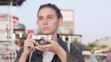 Plajda elinde antika bir kamerayla gün batımını fotoğraflayan bir kız.