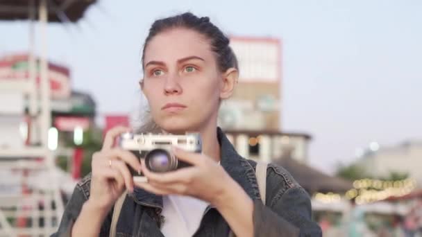 Chica en la playa con una cámara vintage, fotografiando el atardecer — Vídeo de stock
