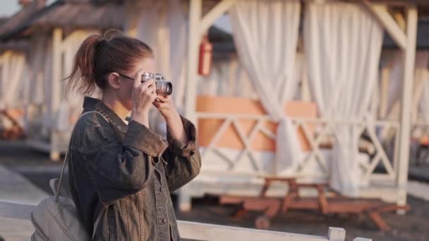 ビンテージカメラでビーチの女の子は、夕日を撮影 — ストック動画
