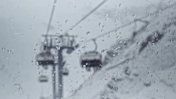 Skigebiet. Blick von der Gondelbahn durch nasses Glas auf die Seilbahn — Stockvideo