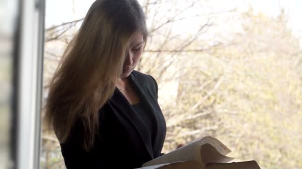 Student tjej läser en bok. utomhus — Stockvideo