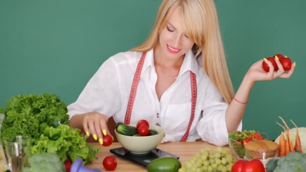 Fit nő mérő vegetabes mérlegen egy asztalnál a zöld háttér — Stock videók