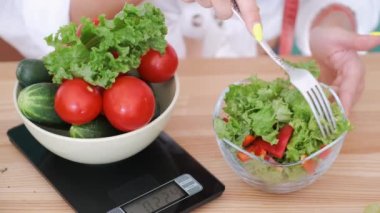 Çatallı ve salata yiyen kadın elleri.