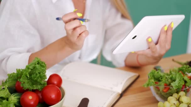 Femme mettant des notes sur le régime alimentaire en regardant la tablette — Video