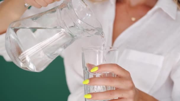 Womans hand pouring fresh pure water from bottle into a glass — Stock Video
