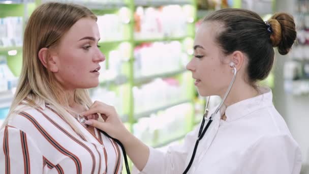 Kvinnlig läkare eller apotekspersonal lyssnar på en patient med stetoskop — Stockvideo