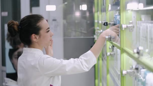 Uma farmacêutica feminina está olhando para alguns produtos na prateleira — Vídeo de Stock