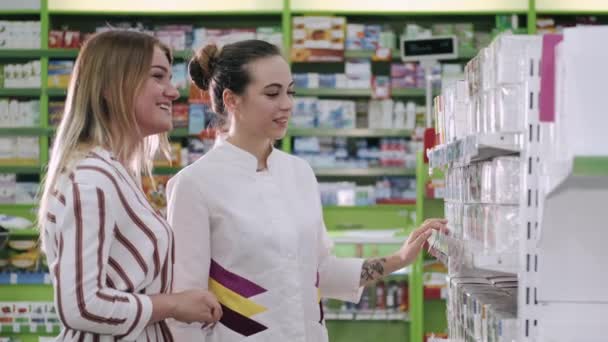 A gyógyszerész és a nő gyógyszereket választ a kereskedelmi polc közelében — Stock videók