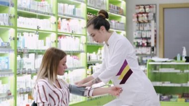 Kadın müşteri eczanedeki kan basıncını kontrol ediyor.