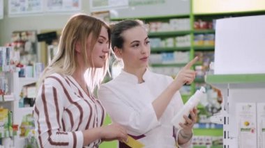Eczacı ve kadın eczanenin yanında ilaç seçiyorlar.