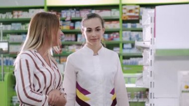 Eczacı ve kadın eczanenin yanında ilaç seçiyorlar.