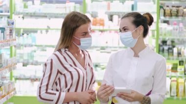 Profesyonel eczacı kadın müşterisine eczanede ürün seçmesinde yardım ediyor.