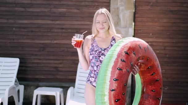 Bella giovane donna che tiene cocktail e anello di nuoto vicino a una piscina — Video Stock