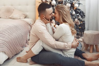 Noel ağacının yanında oturan zarif bir çift.