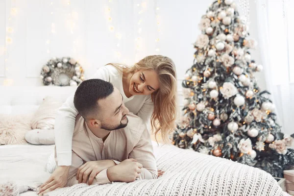 Casal elegante sentado em uma cama em uma decoração de Natal — Fotografia de Stock