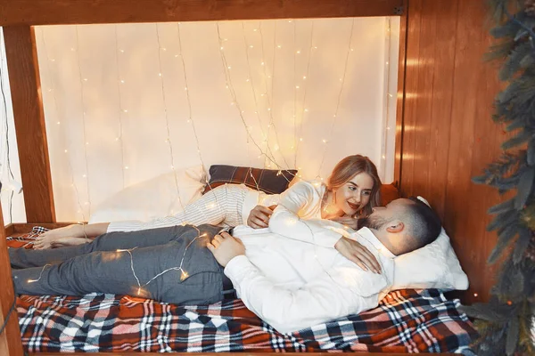 Elegant par sitter med en krans hemma på en säng — Stockfoto