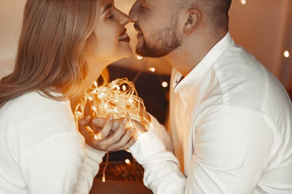 Elegante coppia seduta con una ghirlanda a casa su un letto — Foto Stock